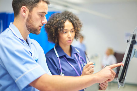 Technician and nurse examine electronic touch tablet